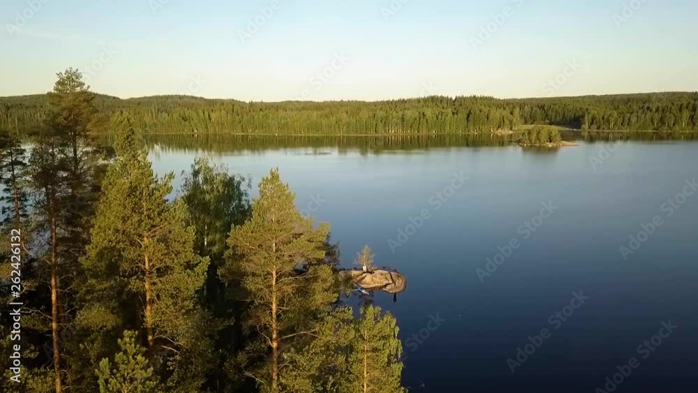 Aerial, tilt, drone shot, over green, pine trees, revealing two kayaks parked at a rocky shore, at lake Saimaa, on a sunny, summer day, in South Karelia, Finland Aerial, tilt, drone shot, over green, pine trees, revealing two kayaks parked at a rocky shore, at lake Saimaa, on a sunny, summer day, in South Karelia, Finland