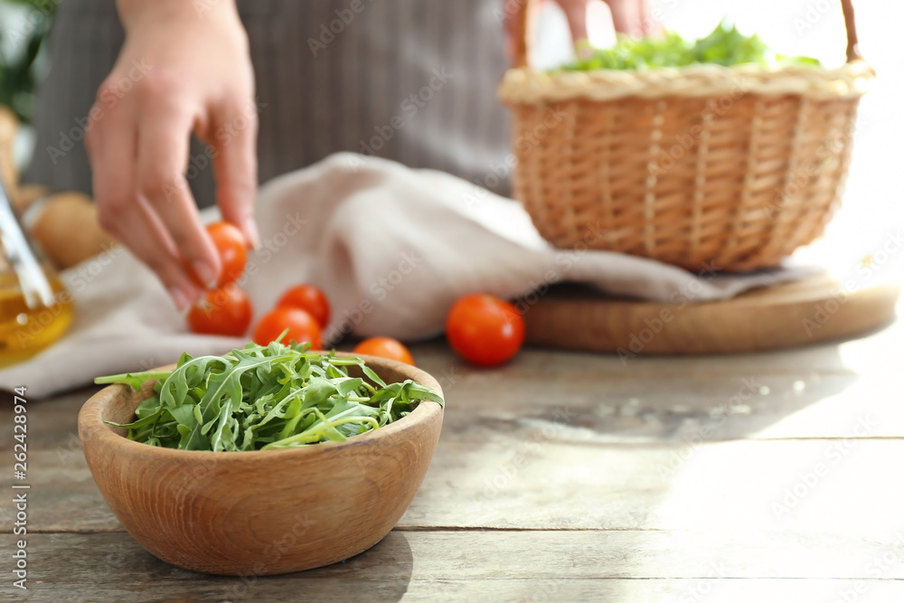 Bowl with tasty fresh arugula on wooden table Bowl with tasty fresh arugula on wooden table
