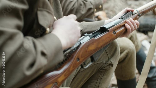 Cinematic close-up shot of a soldier in the form of world war II reloading the bolt of an ancient rifle against the background of another fighter. The concept of a break between fights