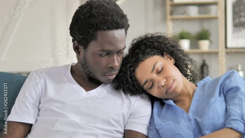 Pensive African Man with Sleeping Girlfriend on Soulder photo