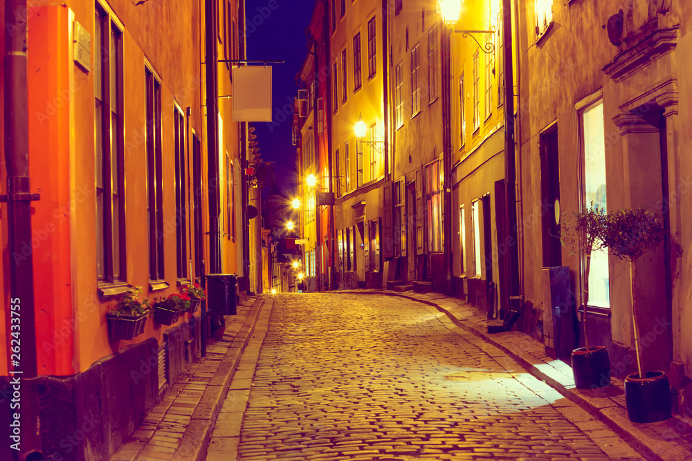 The narrow cobblestone street with medieval houses of Gamla Stan historic old center of Stockholm in the evening twilight sunset. Toned image
