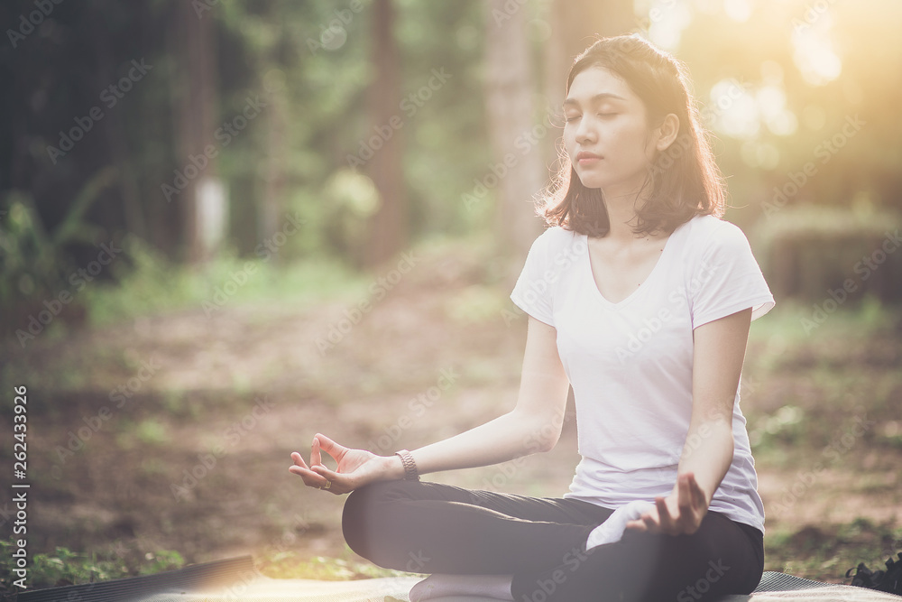 Young woman sitting and doing yoga pose with sunset and forest background. Young woman sitting and doing yoga pose with sunset and forest background.