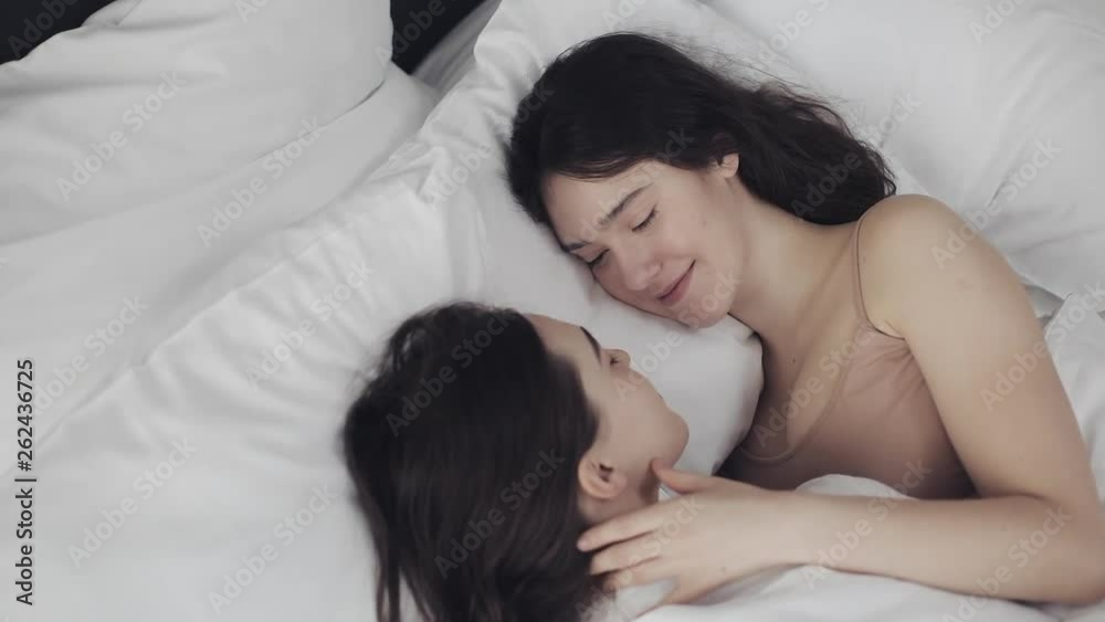 Lesbian couple hugging and smiling while lying together in ...