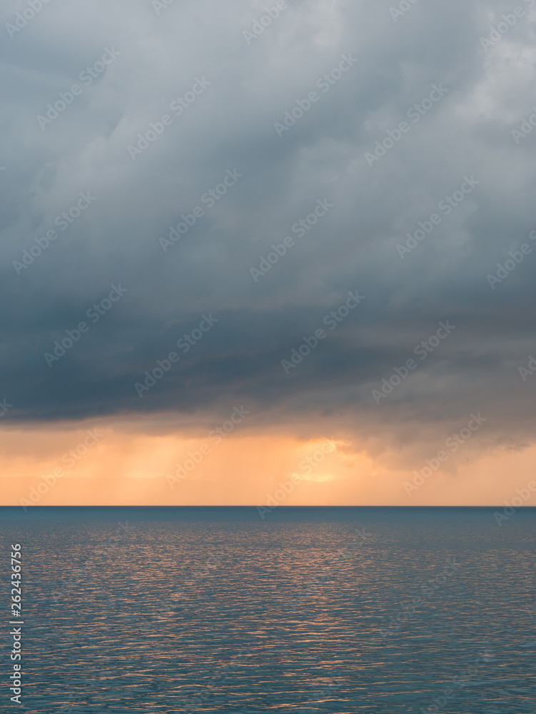 Horizon over blue sea with dark clouds above
