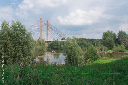 orange suspension, wire bridge Zaltbommel, called Martinus Nijhoff brug, The Netherlands. with trees and ditch © Corinne