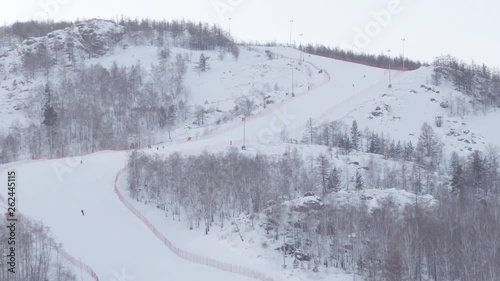 People ride on a new winding ski slope at winter cloudy day - Aerial Footage photo