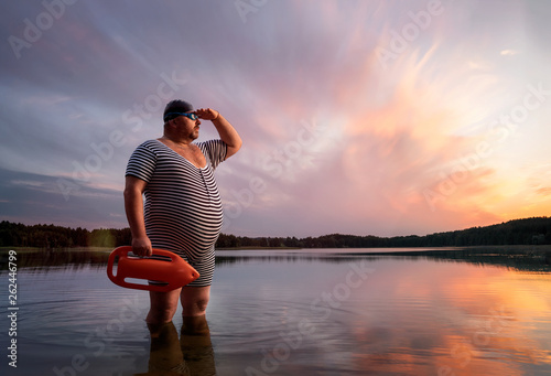 Funny retro lifeguard standing in the water and looking away with copy space