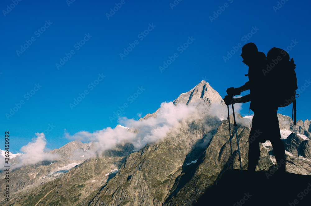 Silhouette hiking man with backpack and trekking pole, over European Alps on the background. Silhouette hiking man with backpack and trekking pole, over European Alps on the background.
