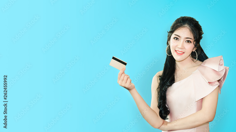 Portrait of young asian woman showing credit card with copy space blue background Portrait of young asian woman showing credit card with copy space blue background