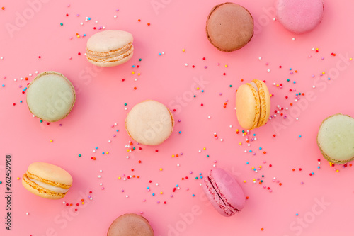 Brignt macarons for sweet break on pink background top view pattern