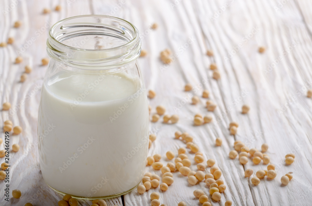 Non-dairy alternative Soy milk or yogurt in mason jar on white wooden table with soybeans aside Non-dairy alternative Soy milk or yogurt in mason jar on white wooden table with soybeans aside