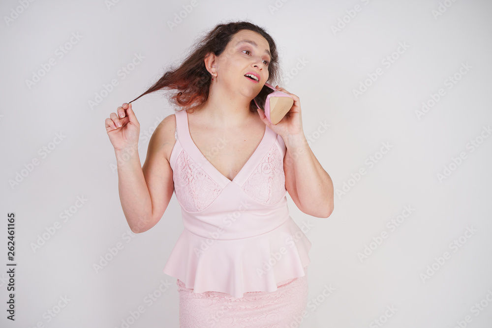 emotional plump woman in pink dress talking and gossips on the Shoe like on the phone on a white Studio background emotional plump woman in pink dress talking and gossips on the Shoe like on the phone on a white Studio background