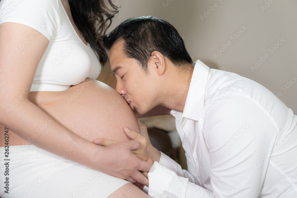 Asian couple pregnant wife and husband kissing on belly woman. Asian couple pregnant wife and husband kissing on belly woman.