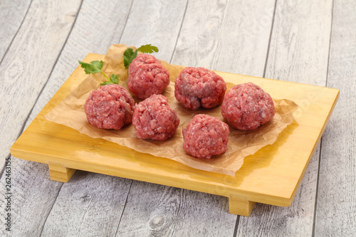 Raw meatball over wooden background