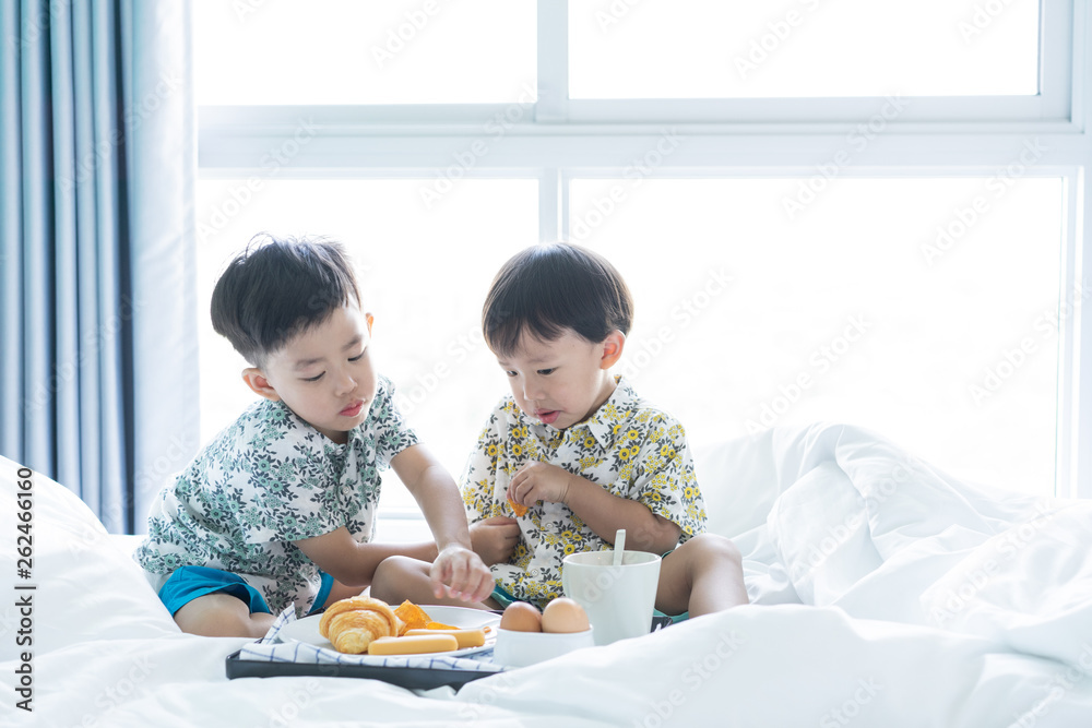 Brothers are sharing breakfast on the bed in the morning. Brothers are sharing breakfast on the bed in the morning.