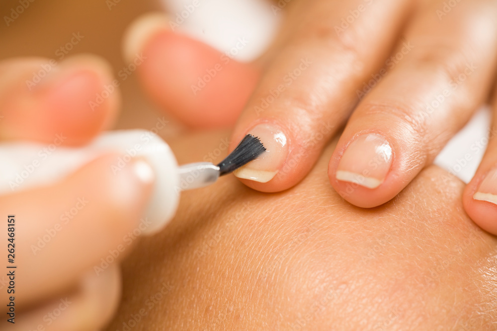woman applying a nail polish on her fingernails woman applying a nail polish on her fingernails
