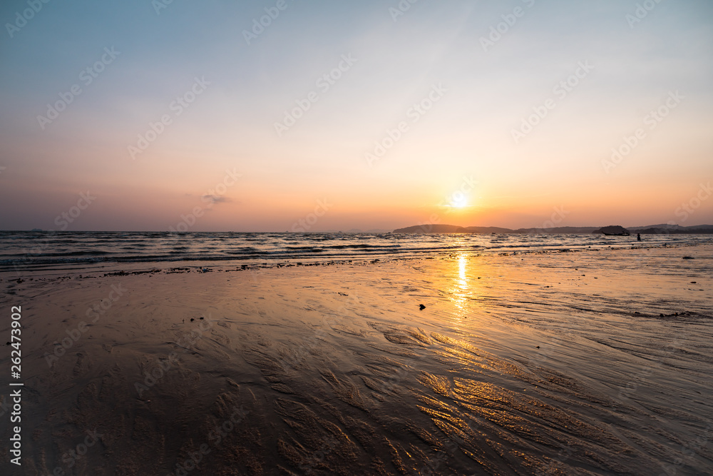 Panoramic photo of beautiful sunset over the sea, sun goes behind the mountain.