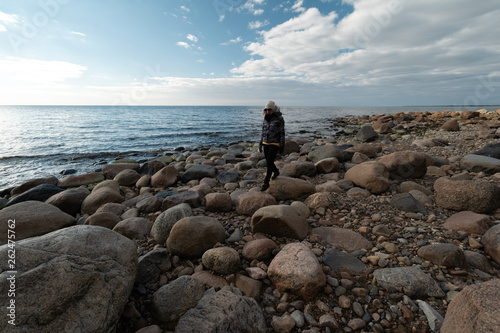 Young archaeologist on a boulder beach looking for exotic rocks on a coastline of a Baltic Sea