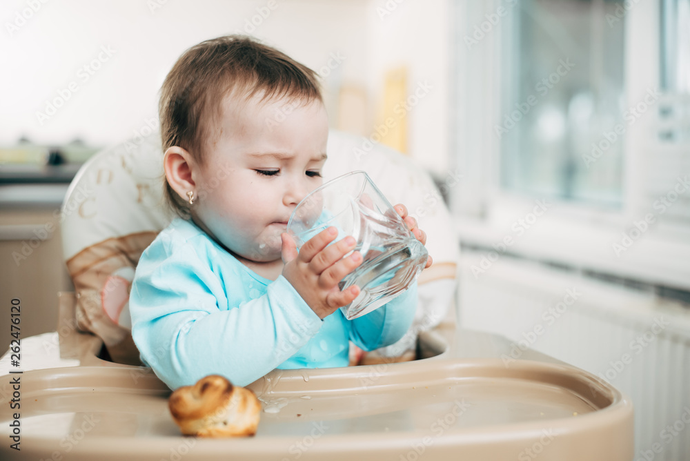 Cute little girl sitting in baby chair and drinking water Cute little girl sitting in baby chair and drinking water