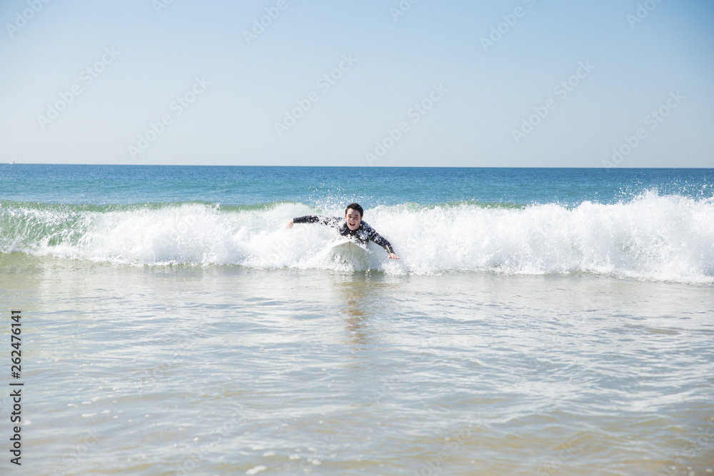 Happy young man swimming on surf board in ocean