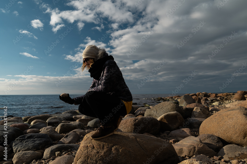 Young archaeologist on a boulder beach looking for exotic rocks on a coastline of a Baltic Sea Young archaeologist on a boulder beach looking for exotic rocks on a coastline of a Baltic Sea