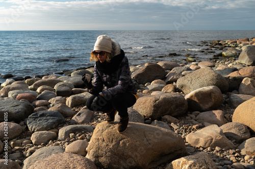 Young archaeologist on a boulder beach looking for exotic rocks on a coastline of a Baltic Sea