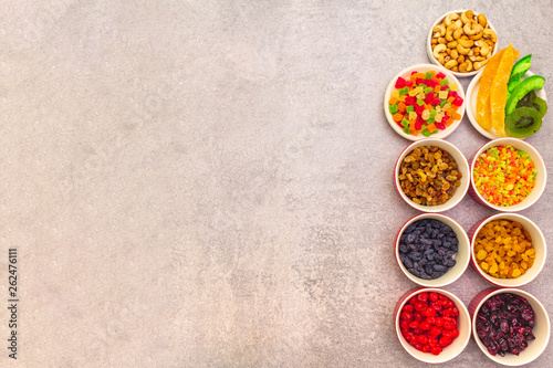 Dried and candied fruit and cashew nuts. Assorted in ceramic bowls on a stone background. Healthy vegetarian (vegan) food concept, copy space, top view.