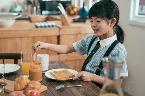 Peanut butter sandwich toast bread on wooden table kitchen at home morning. smiling happy little kid elementary school student in uniform before study eating breakfast. cute child having healthy meal photo