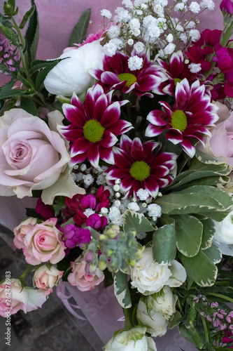 A top down view of bunches of multi-coloured flowers and roses for sale at a local market, including pink, red and purple