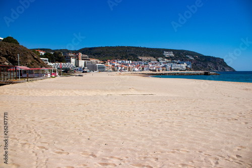 Gold beach with village in background under blue sky © Artur Gomes