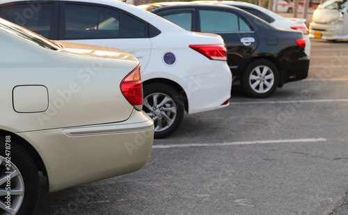 Closeup of rear, back side of golden car with other cars parking in outdoor parking lot.