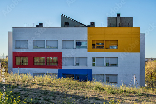 A building with a facade of several colors isolated behind a meadow in Madrid. Spain.