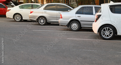 Closeup of rear, back side of white car with other cars parking in outdoor parking lot.