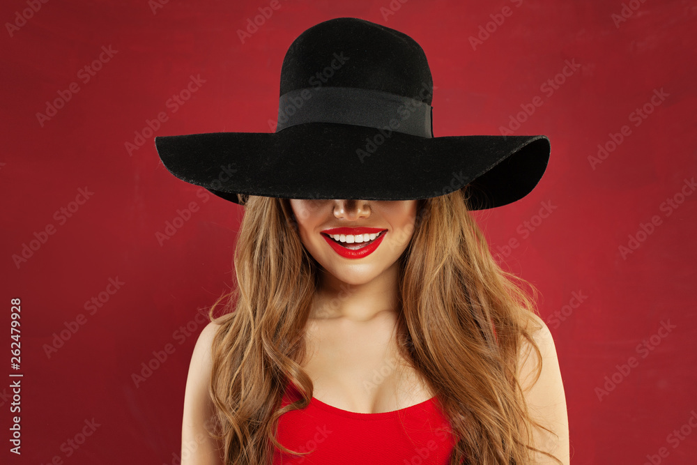 Smiling woman in black hat on red background. Beautiful happy model portrait Smiling woman in black hat on red background. Beautiful happy model portrait