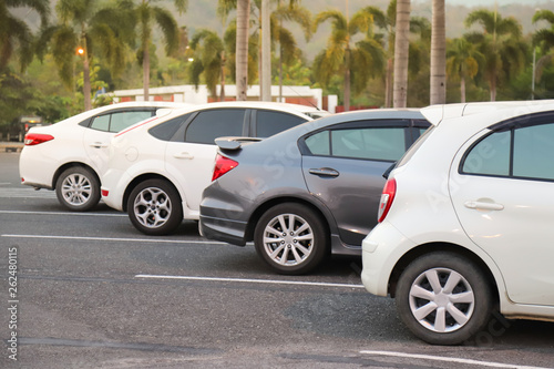 Closeup of rear  back side of white car with  other cars parking in outdoor parking lot with natural background in twilight evening. 