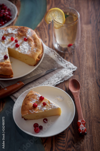 Cheesecake with cranberries and sugar, green tea and lemon on wooden table