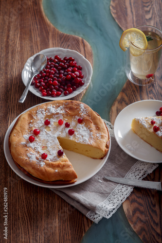 Cheesecake with cranberries and sugar, green tea and lemon on wooden table