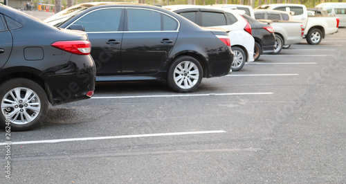 Closeup of rear, back side of black car and other cars parking in outdoor parking lot in twilight evening.  © Amphon