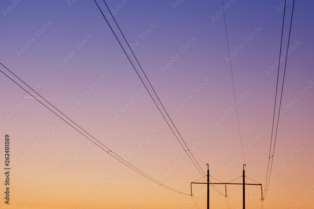 electrical wires against the dawn sky, in the background two pillars, focusing on the wires, concept