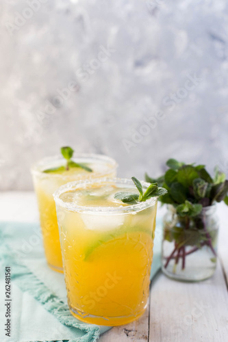 Refreshing homemade lemonade with ice, lime and mint.  on a white wooden table.