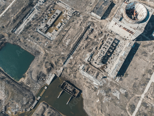 Aerial view from drone of abandoned and ruined Nuclear Power Plant or station, round tower of atomic reactor, large industrial demolished building photo