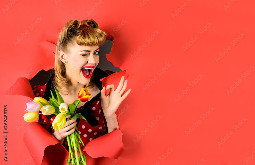 Pin up woman looking through paper showing ok sign. Winking woman through paper shows ok gesture. Pin up woman holds flowers. Bouquet of flowers. Breaking paper. Sale. Discount. Spring flowers. Tulips Pin up woman looking through paper showing ok sign. Winking woman through paper shows ok gesture. Pin up woman holds flowers. Bouquet of flowers. Breaking paper. Sale. Discount. Spring flowers. Tulips