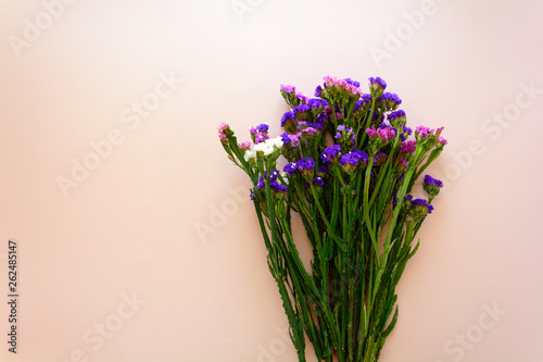 Bouquet of sea lavender flowers (Limonium) lying on pink background. Top view. Copy space