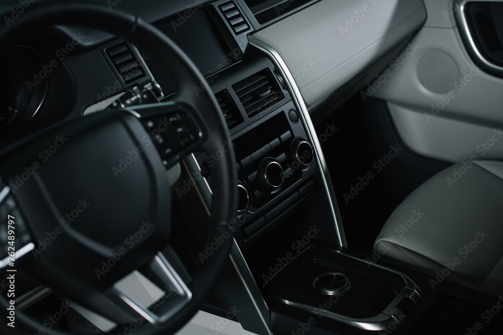 selective focus of buttons near black steering wheel in luxury car