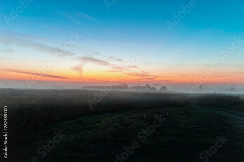 early morning, the sky in the color of dawn before sunrise, field covered with morning mist