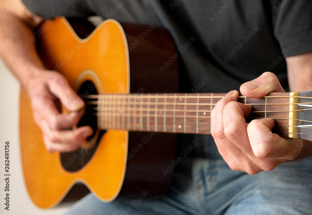 Man strumming a C Chord whilst playing an Acoustic Guitar