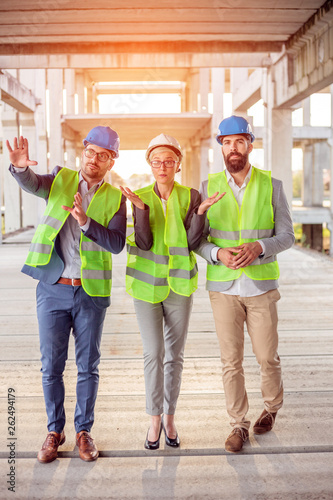 Obraz na płótnie Team of successful young architects and business partners checking work progress on a construction site. Architecture and teamwork concept. w salonie