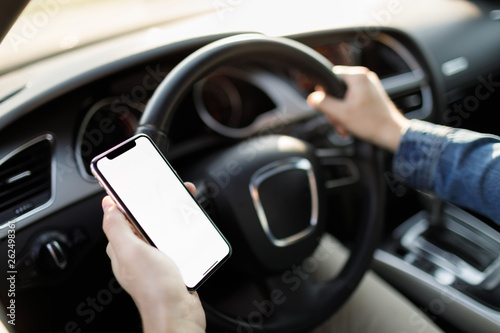 Young business man with phone in car. Man holding smartphone with blank screen .
