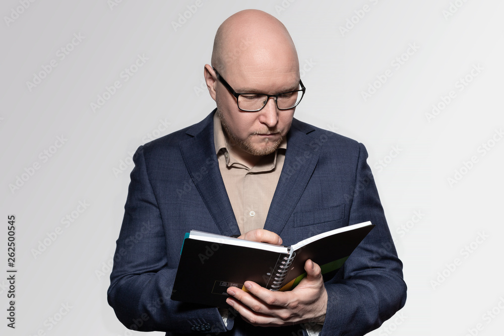 Businessman in glasses makes a note in black notebook during a conference Businessman in glasses makes a note in black notebook during a conference