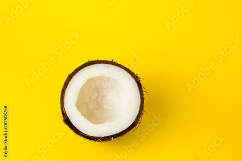Half of Coconut on yellow colored background, flat lay, top view